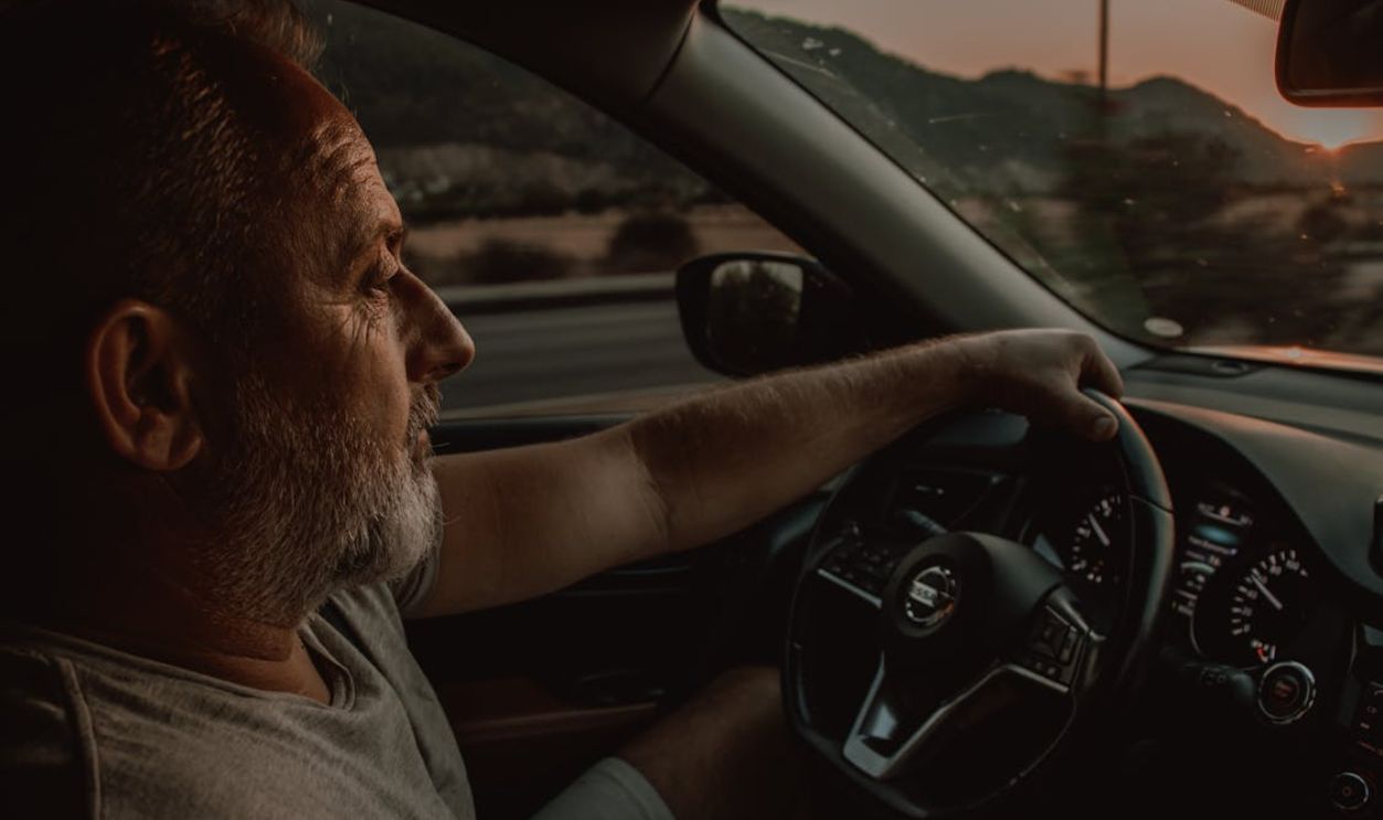 A Man in Gray Shirt Driving a Car