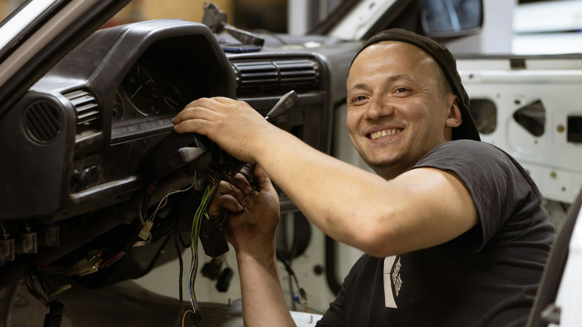 man in black crew neck t-shirt holding black car steering wheel