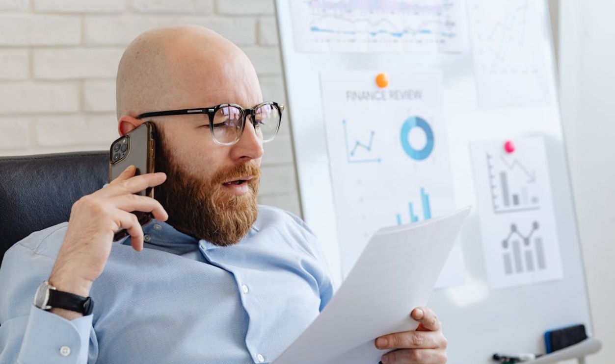 A Man Talking on the Phone While Looking at Documents