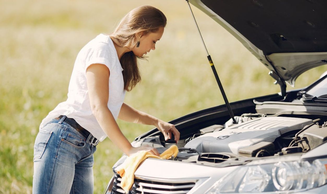 Troubled young woman near broken automobile in countryside during car accident