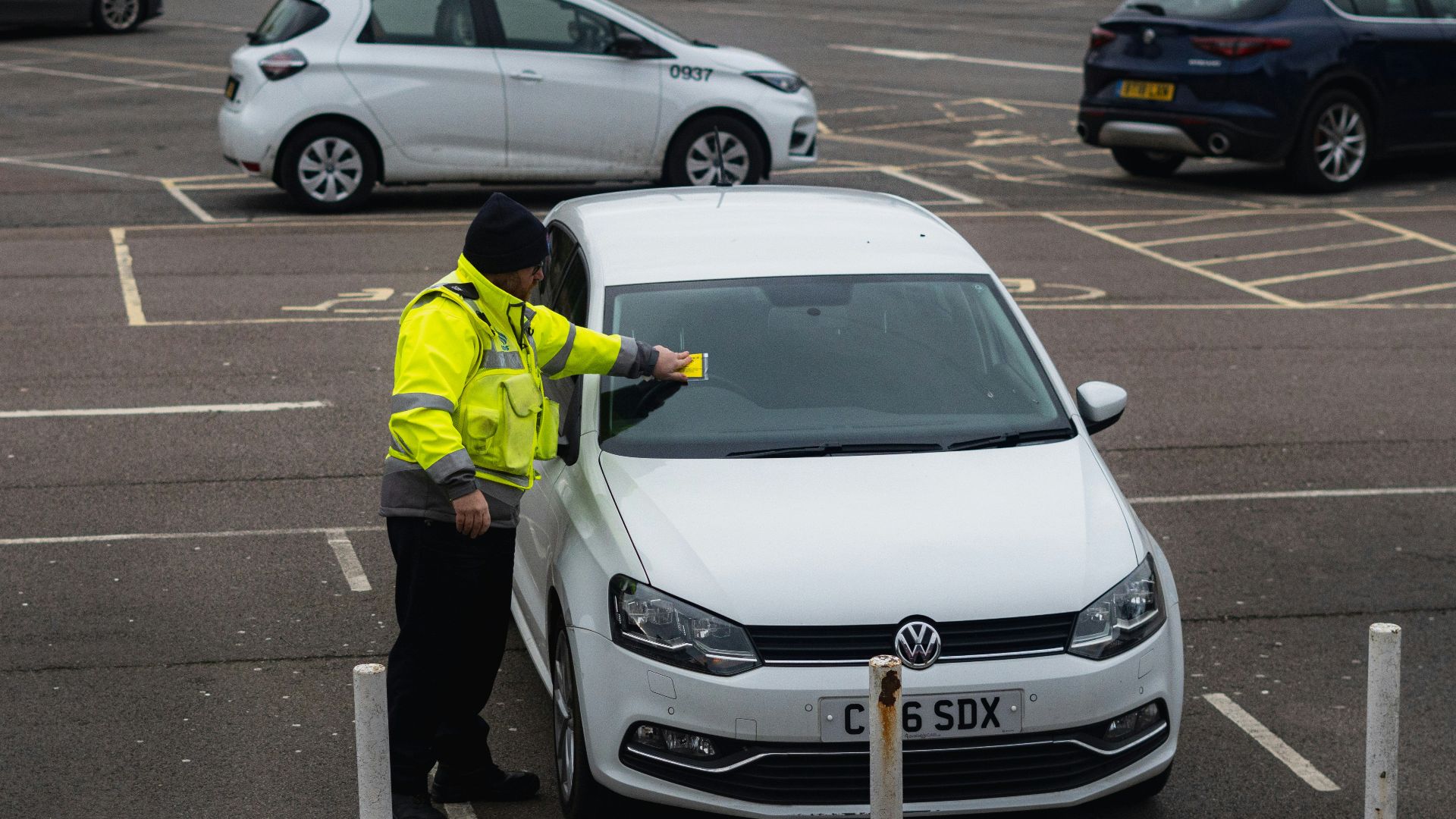 man in yellow jacket standing beside white car