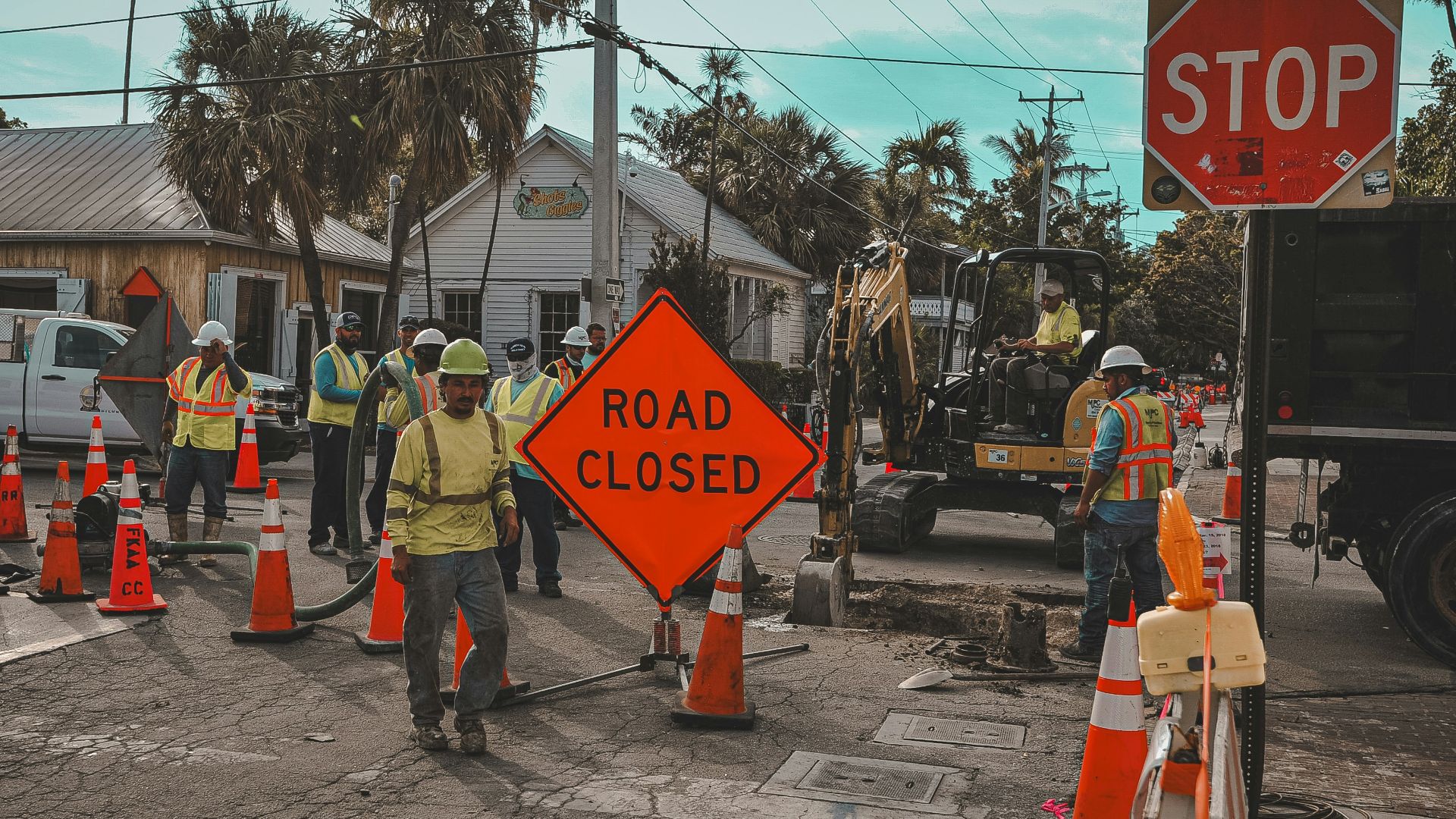 Construction workers and road closed signs on a street.