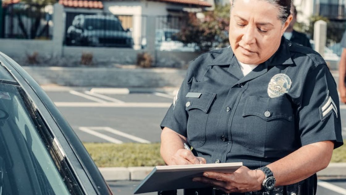 A Police Officer Standing Beside a Car while Holding a Clipboard