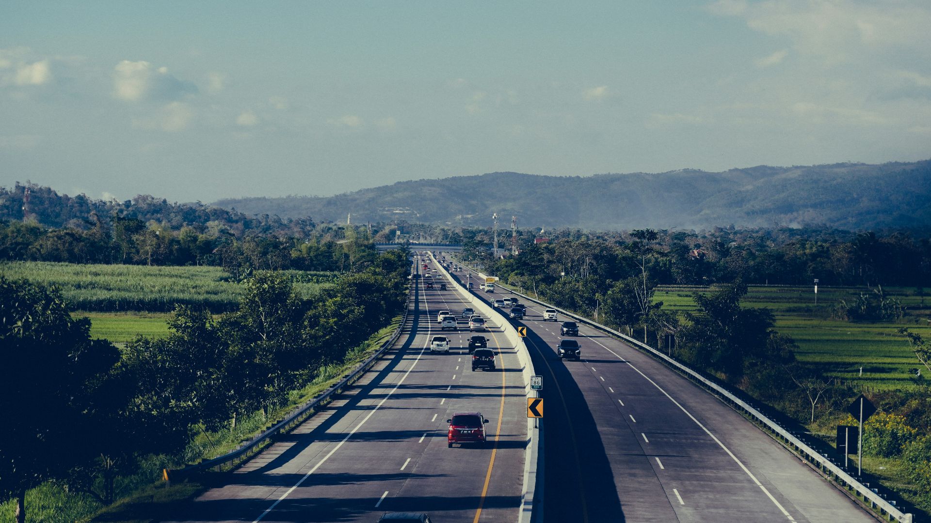 Highway with cars stretches towards distant mountains.