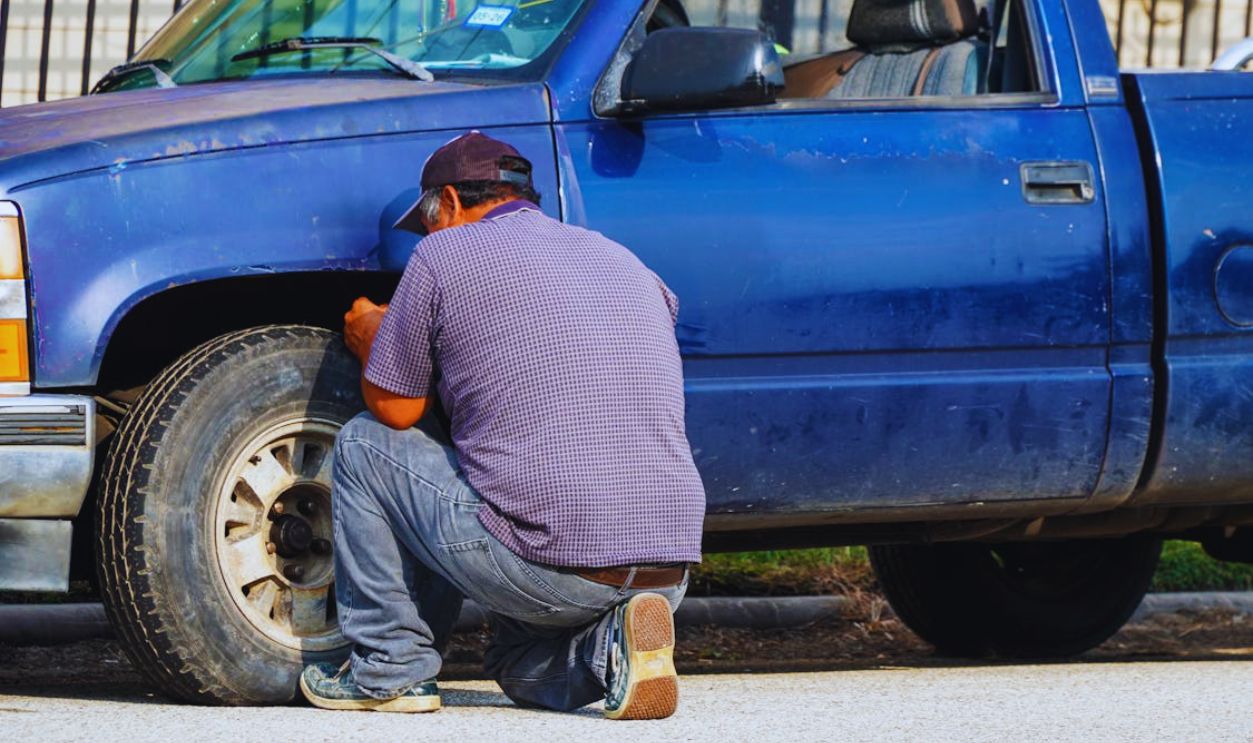 Man Repairing Tire of Blue Truck in Houston