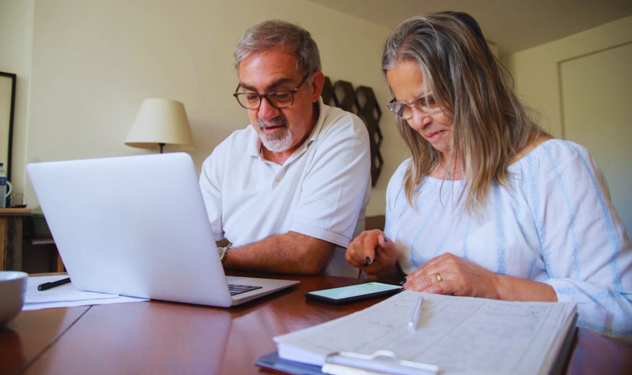 Couple Sitting by the Desk with a Laptop