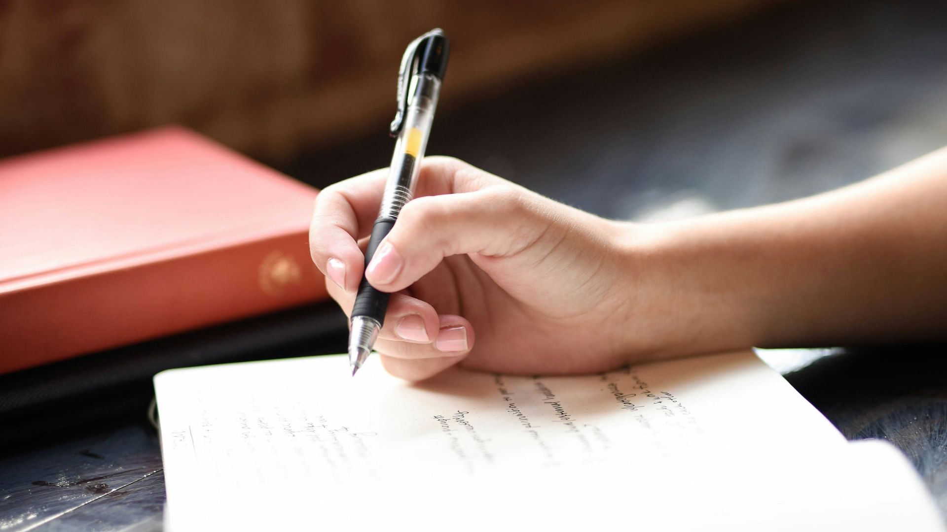a person writing on a piece of paper with a pen