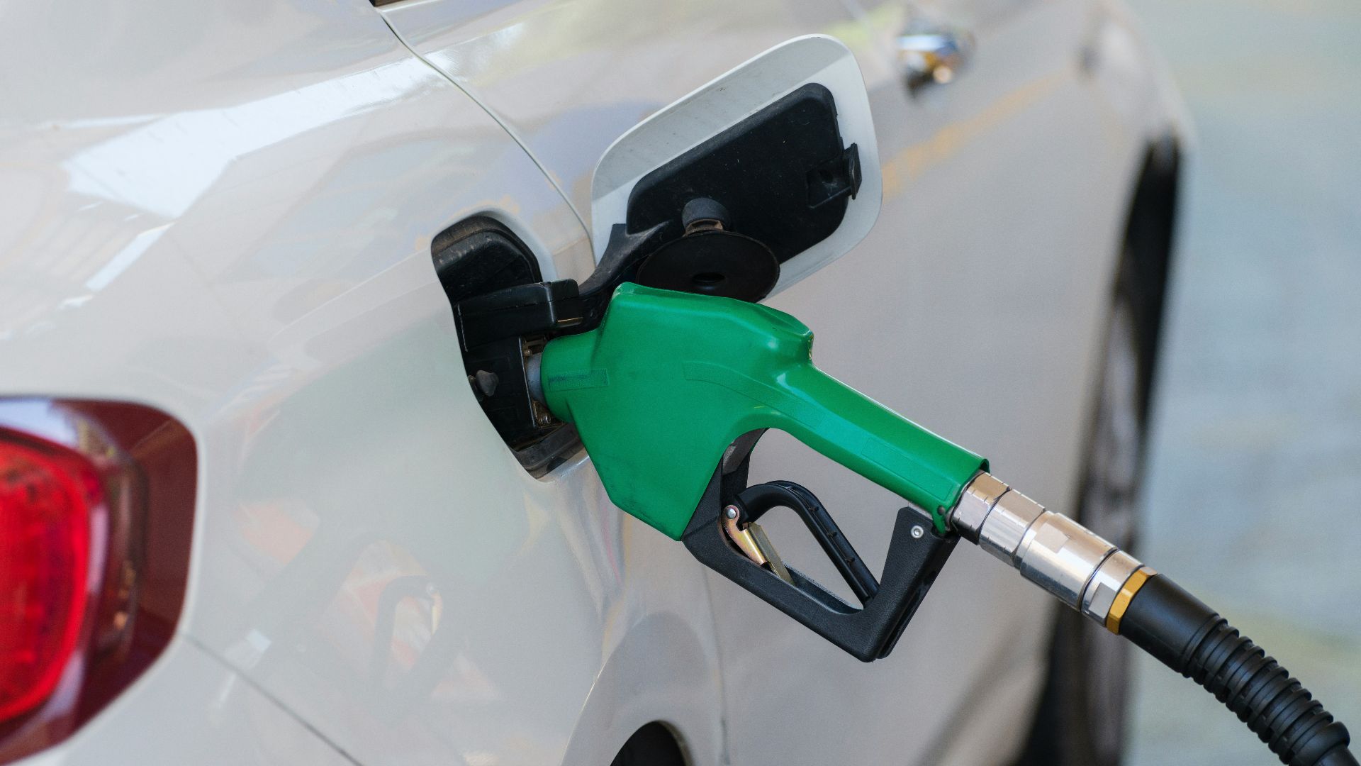a white car with a green gas pump