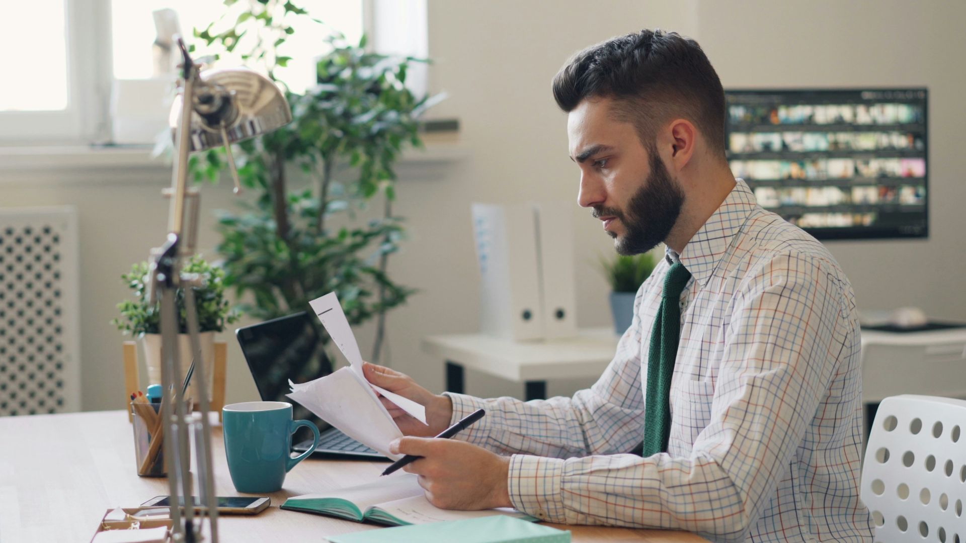 a man sitting at a desk with a laptop and papers