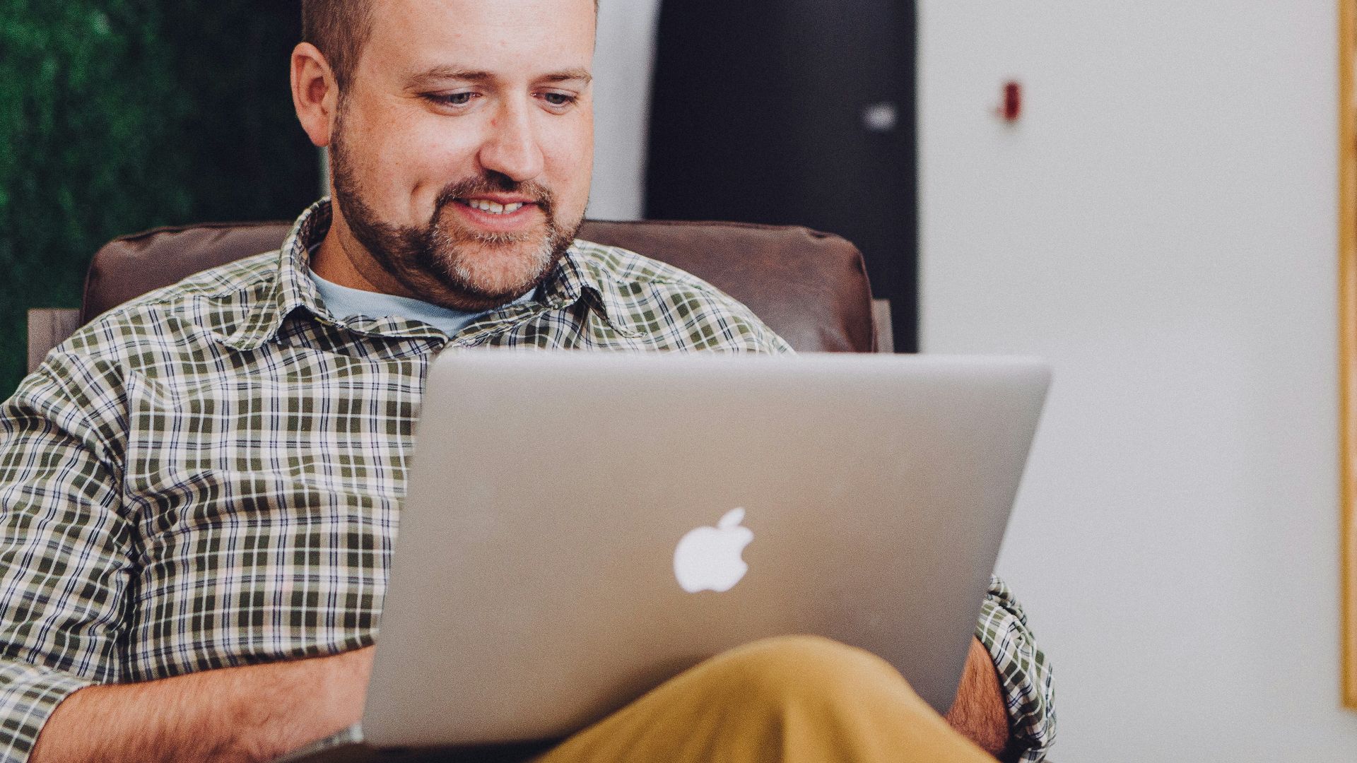 man smiling and using MacBook