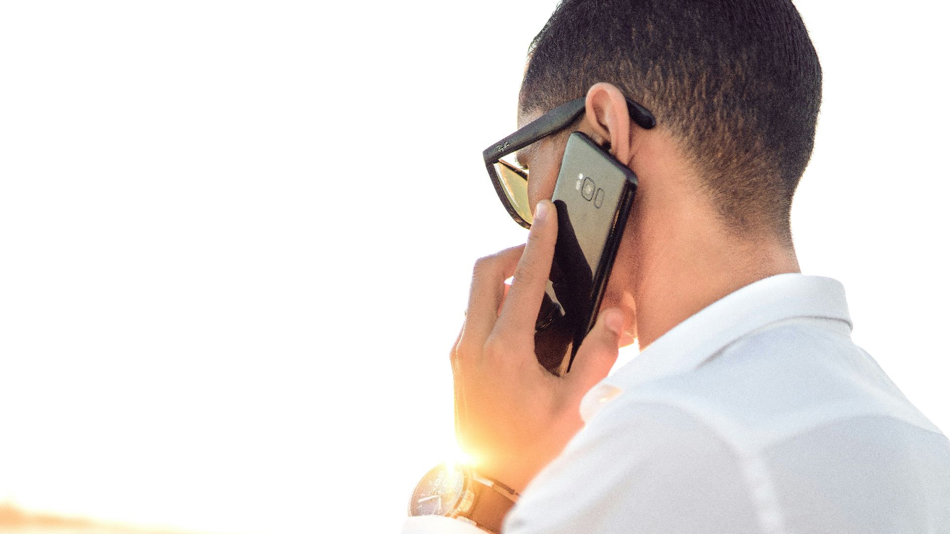 man holding smartphone standing in front of calm body of water