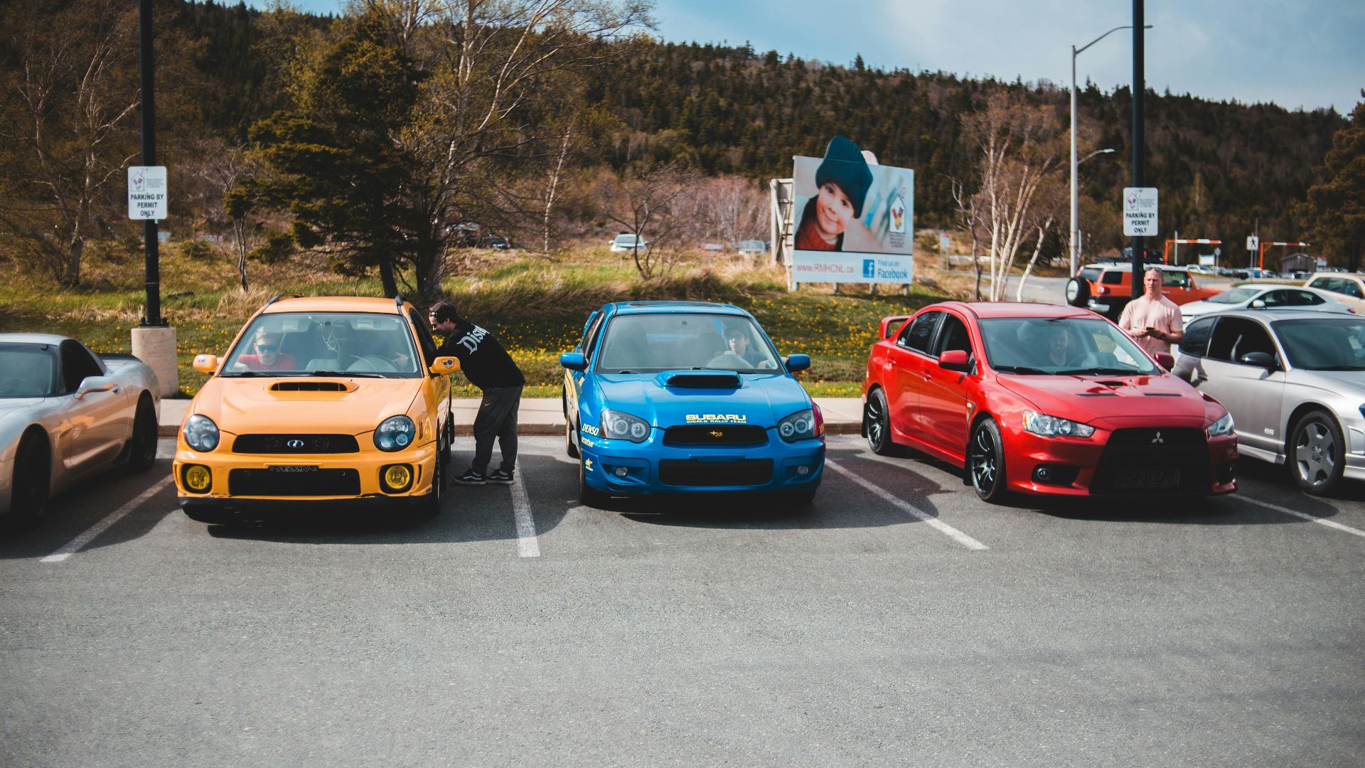 Colorful cars showcased outdoors in an urban parking lot on a sunny day.