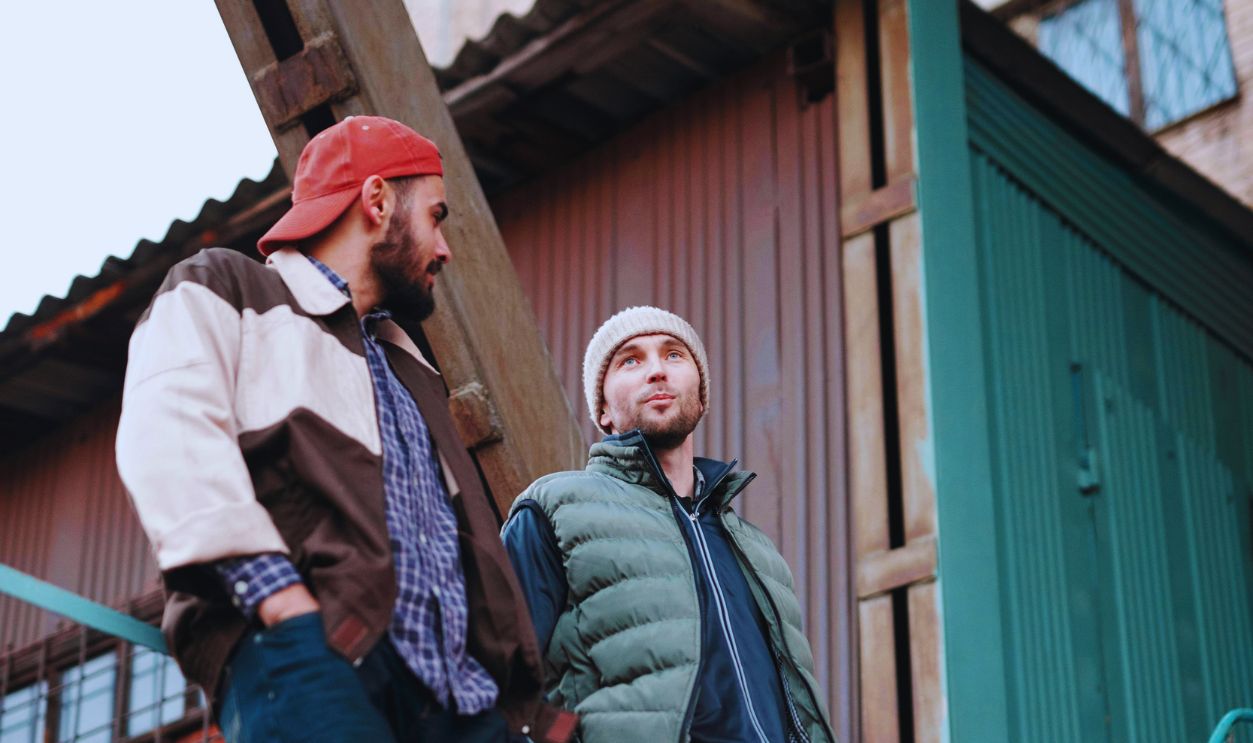 Men Leaning on Metal Railings while Having a Conversation