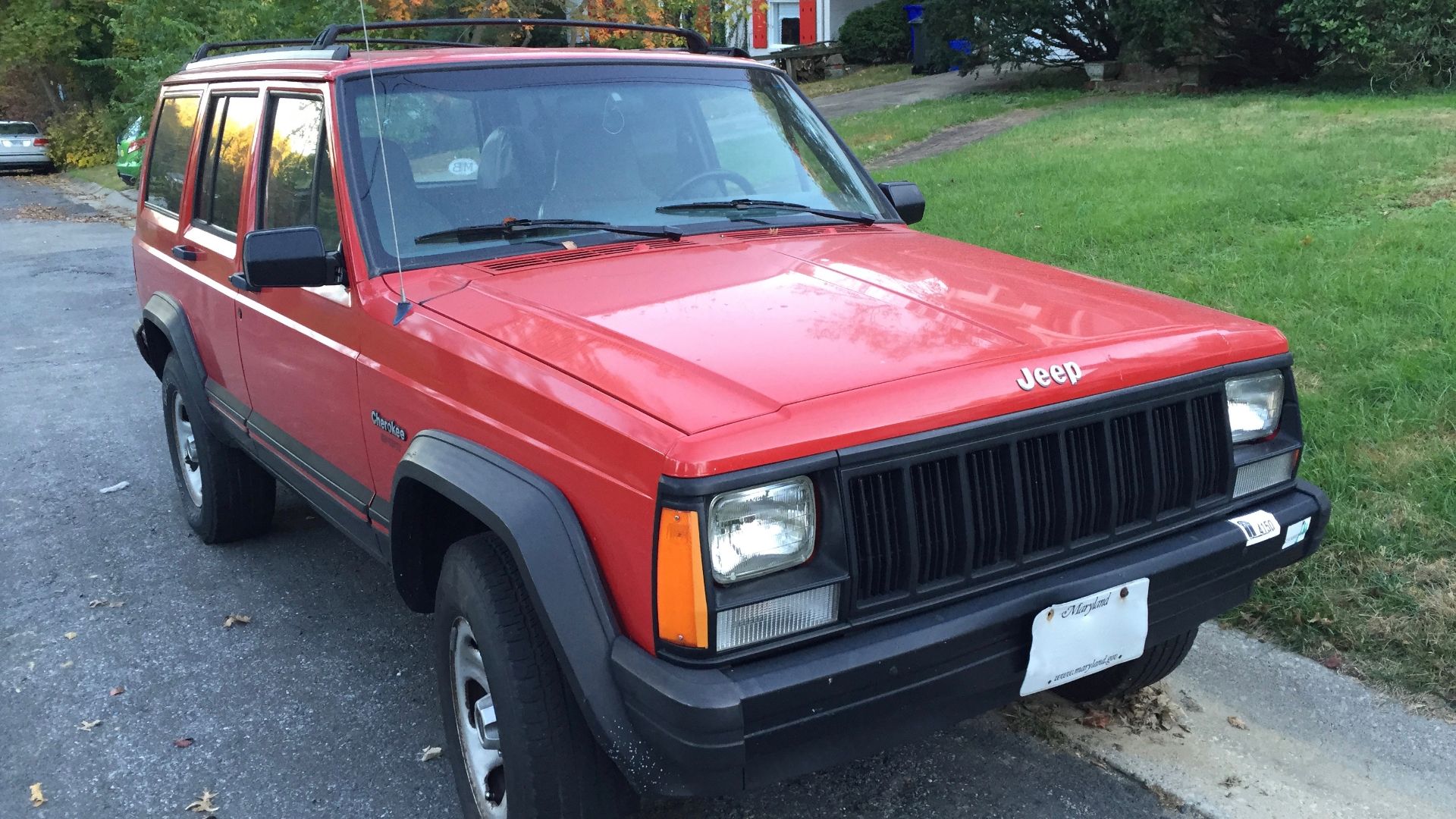 Jeep Cherokee (XJ) 1988–1996, Sport model four-door finished in red. Front right side view.
