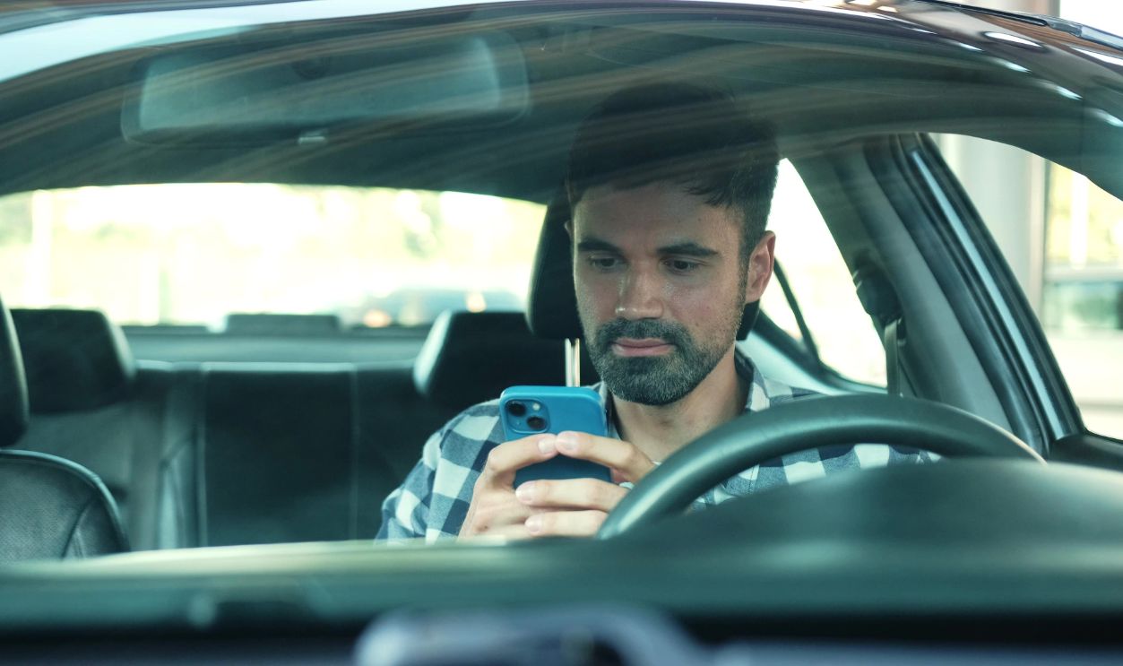 Smiling male driver using mobile phone while sitting in the car. Transport, technology, lifestyle concept.