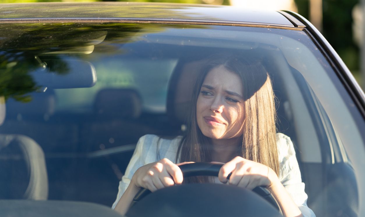 Woman drives her car for the first time, tries to avoid a car accident, is very nervous and scared, worries, clings tightly to the wheel. Inexperienced driver in stress and confusion after an accident