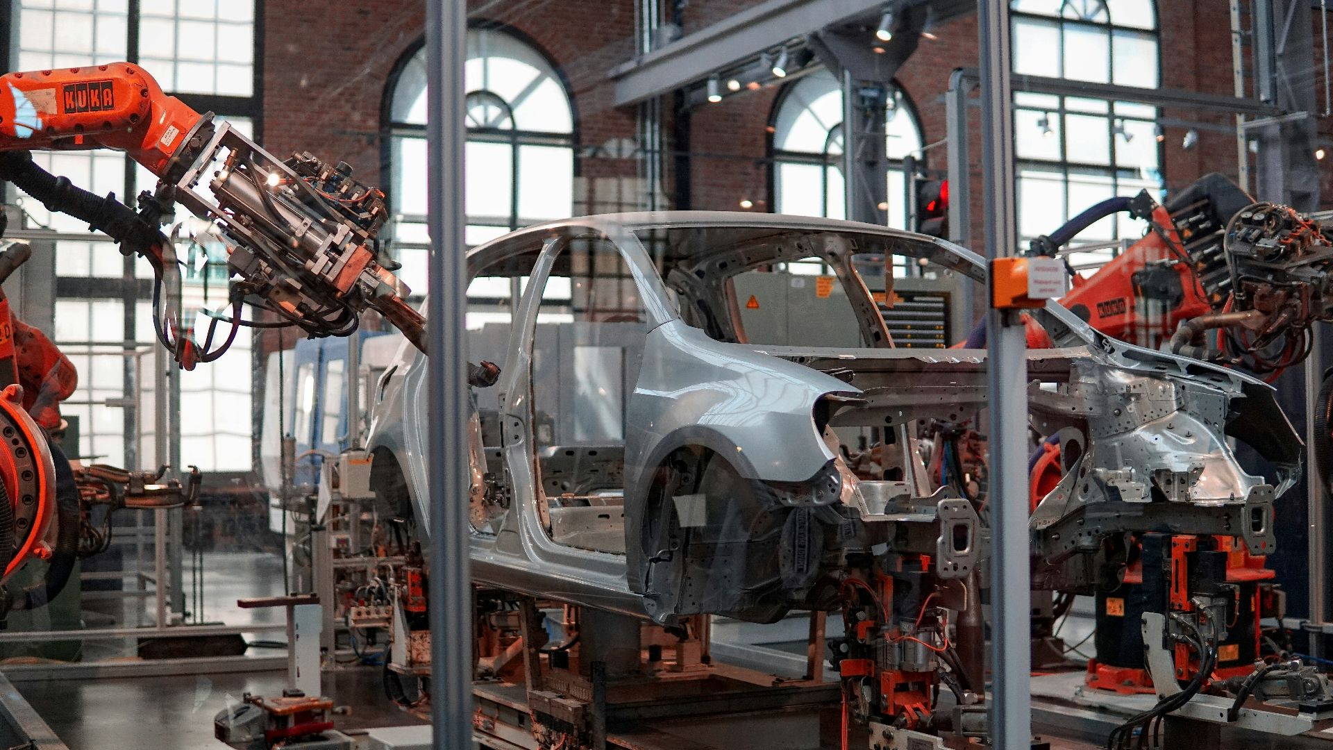 gray vehicle being fixed inside factory using robot machines