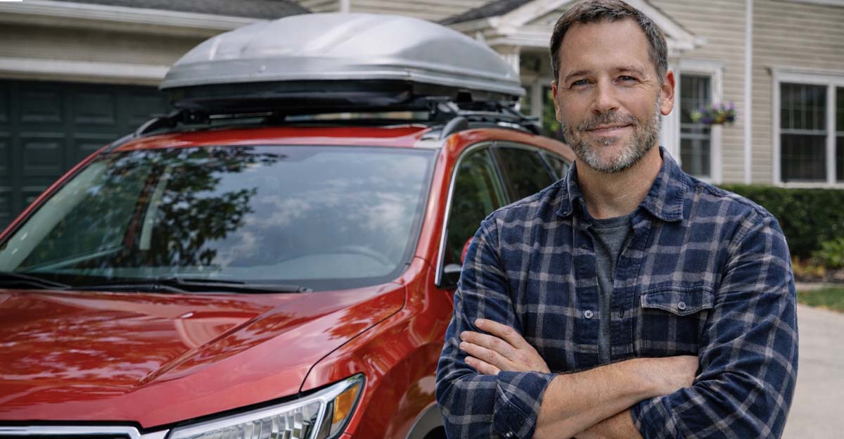 Man with SUV in suburban driveway, ready for a road trip.