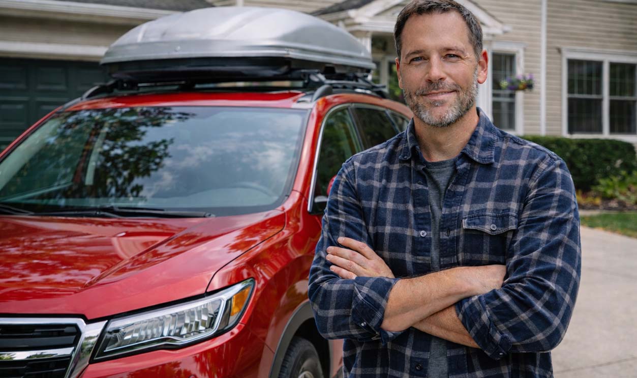 Man with SUV in suburban driveway, ready for a road trip.