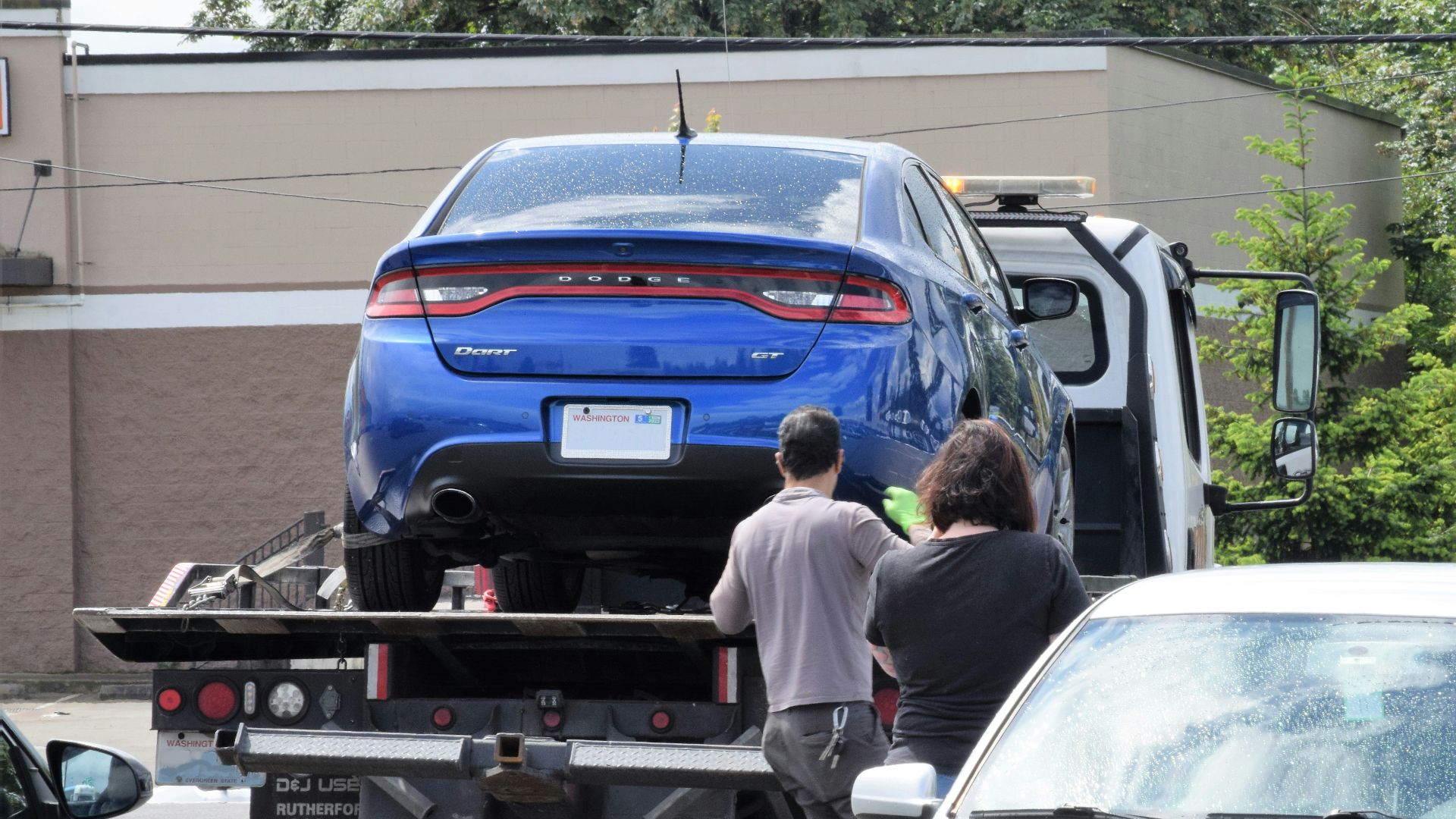 a blue car being loaded onto a flatbed truck