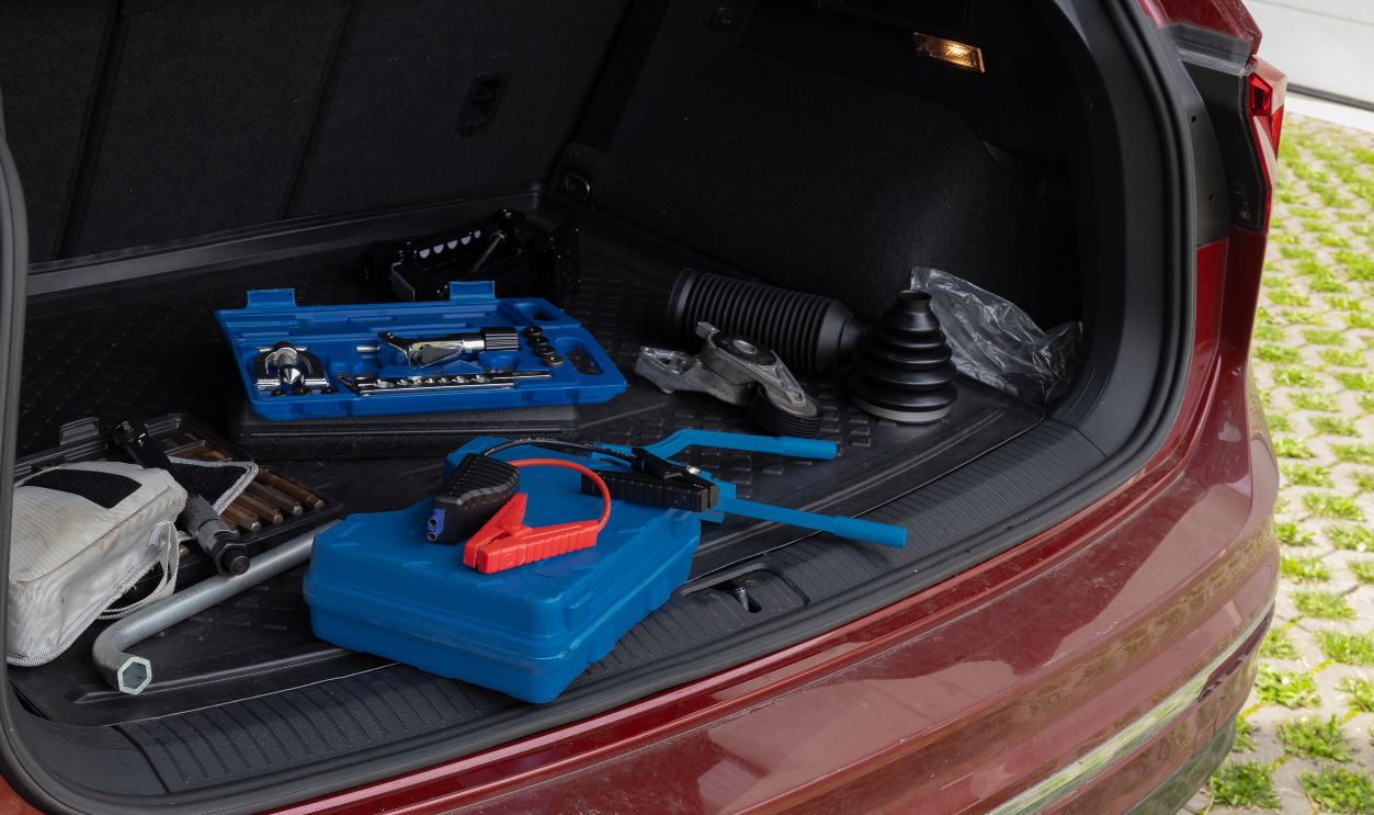 Trunk of car with automotive tools including wrench set and jumper cables