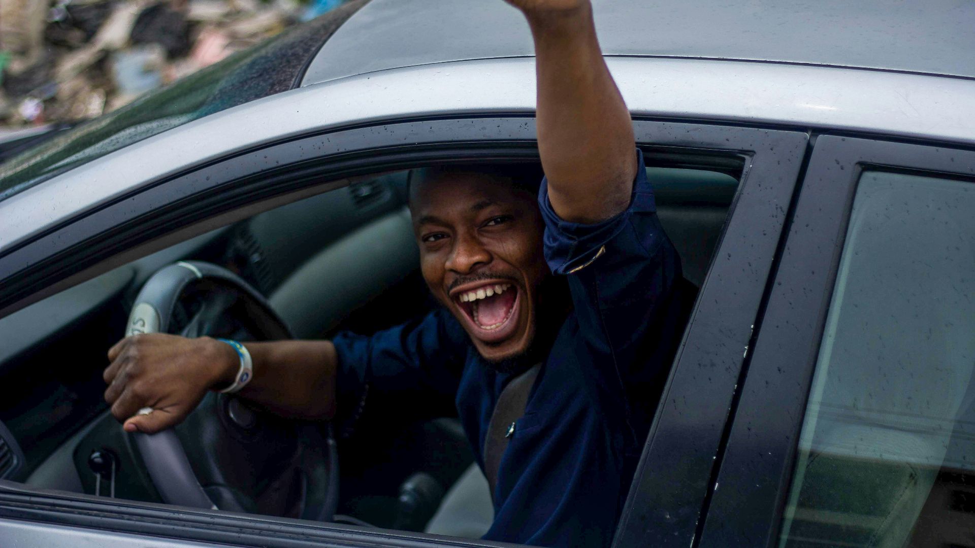 man in black t-shirt and blue denim jeans sitting on car seat
