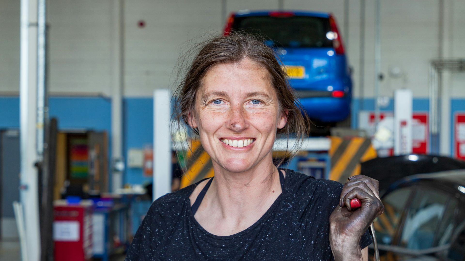 a woman holding a wrench in a garage