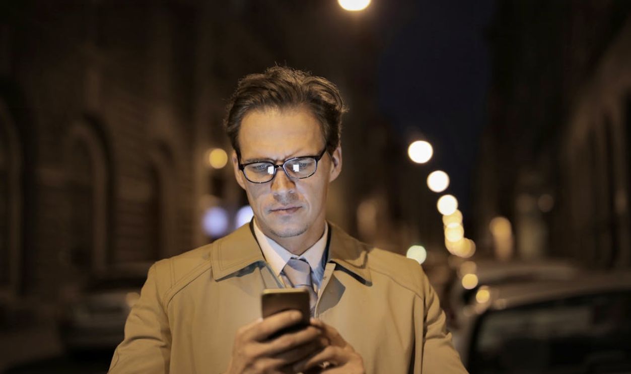 Serious businessman using smartphone on street