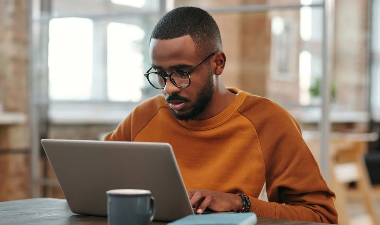 A Man in Sweater Using Laptop