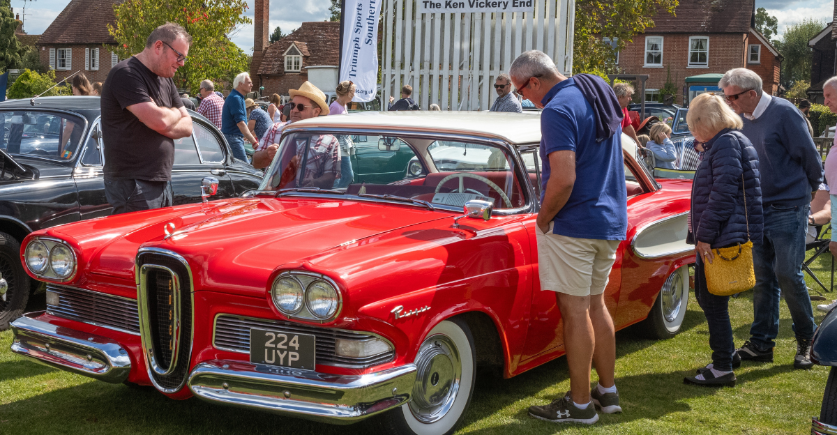 People stop to look at a bright red 1958 Ford Edsel car