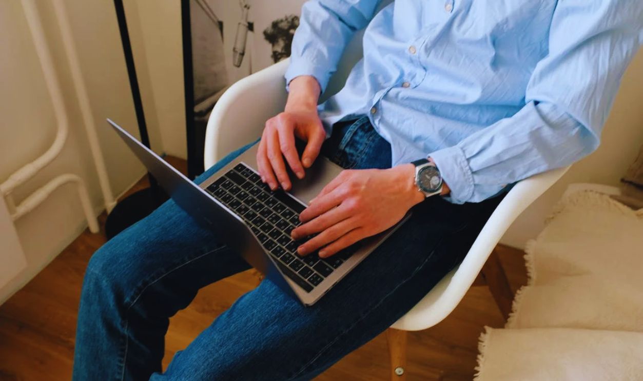 Crop unrecognizable guy browsing laptop in living room