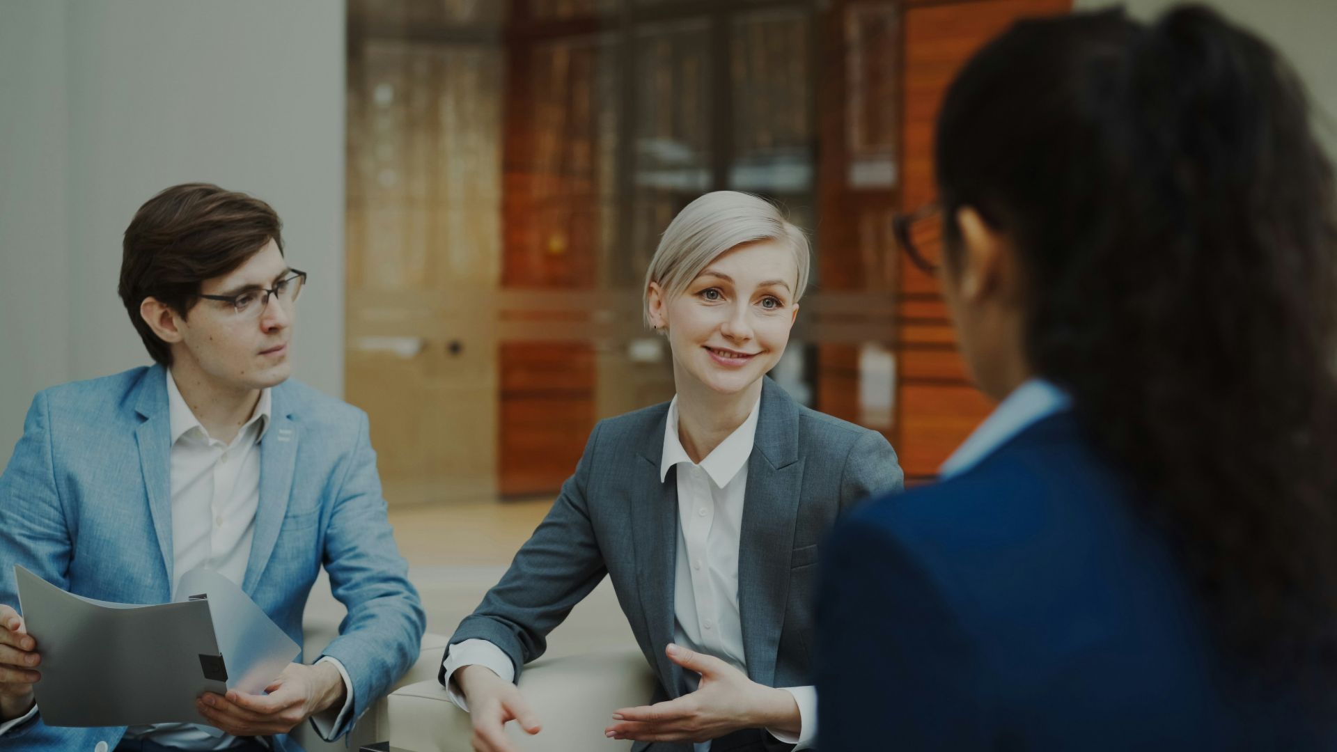 Three people in a business meeting discussing documents