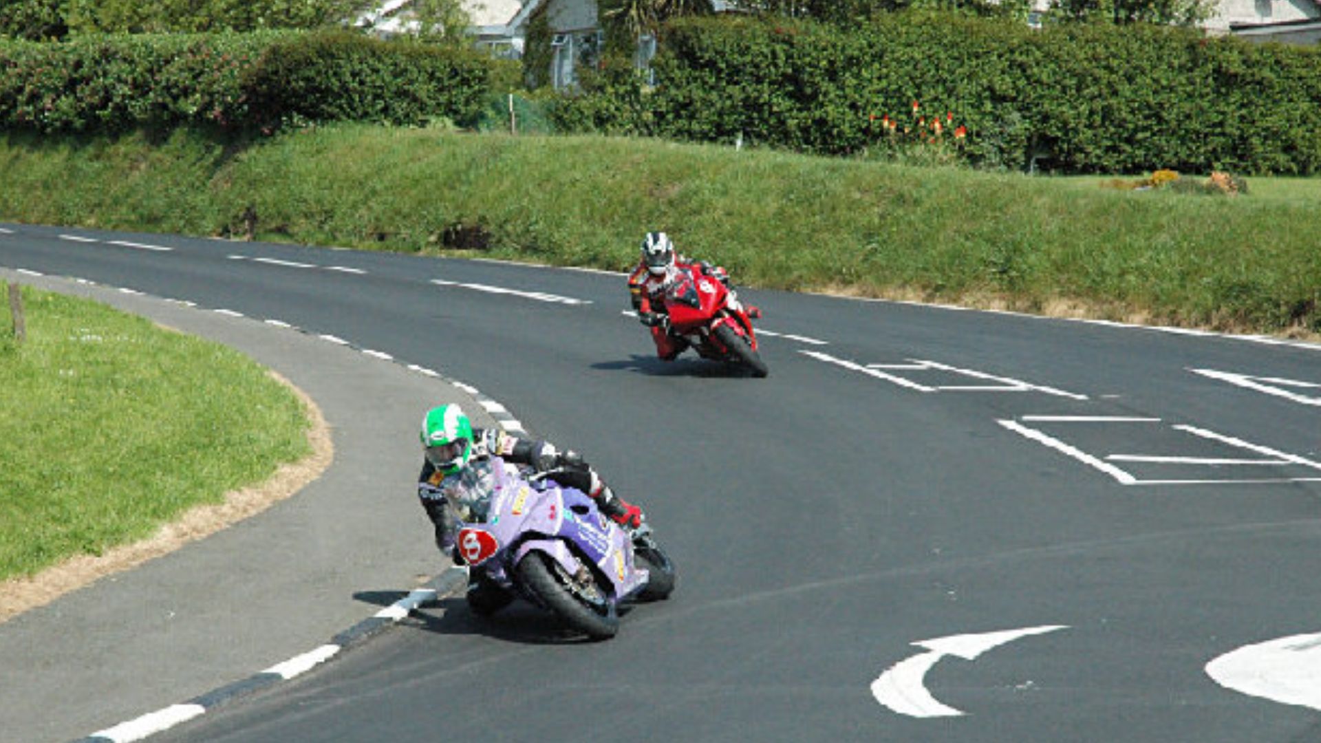 Motorcycle racing at Signpost Corner - Isle of Man - Riders in the TT races near the end of a lap at Signpost Corner