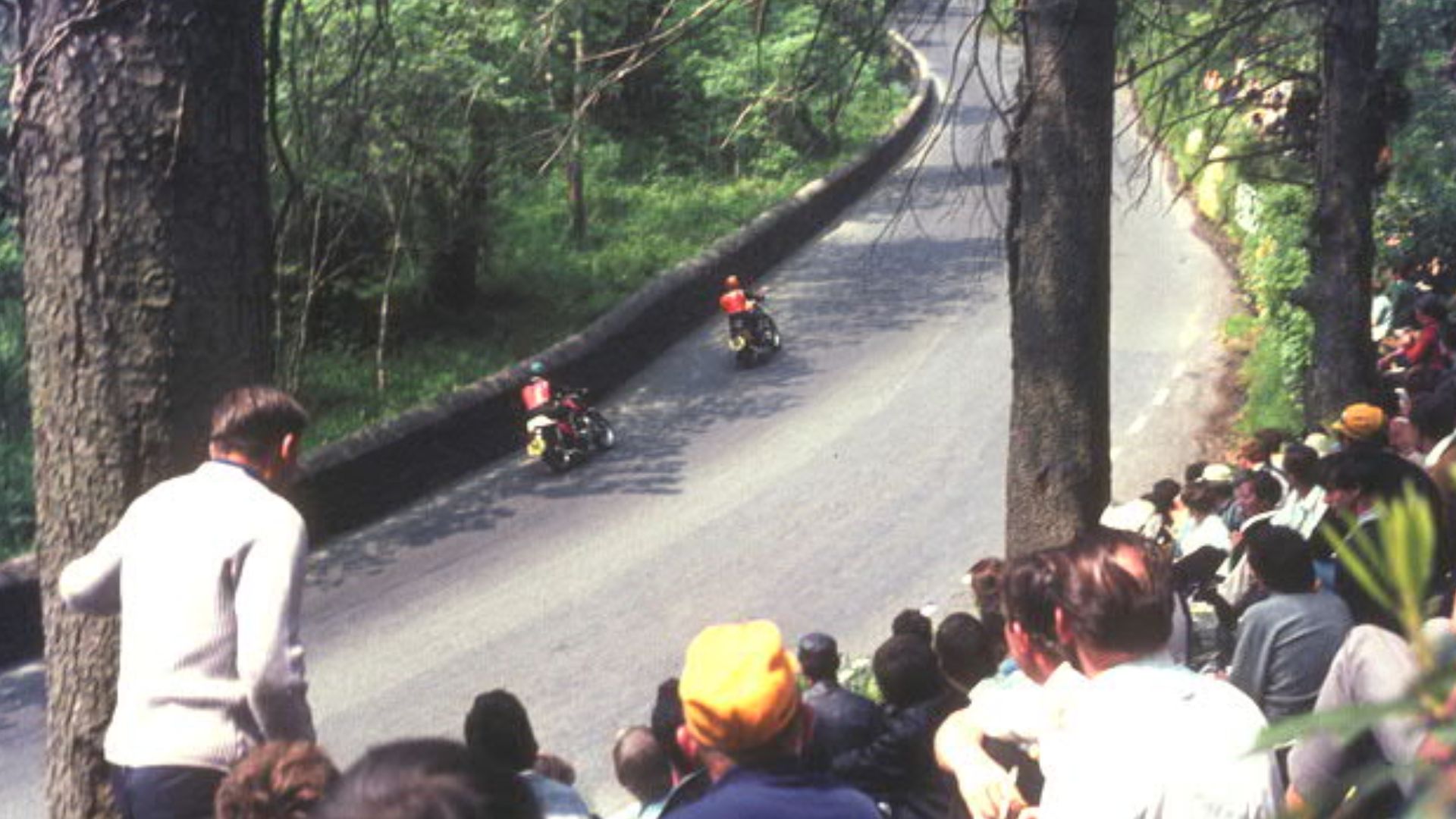 Spectators on the TT course at Glen Helen with two travelling marshals passing by