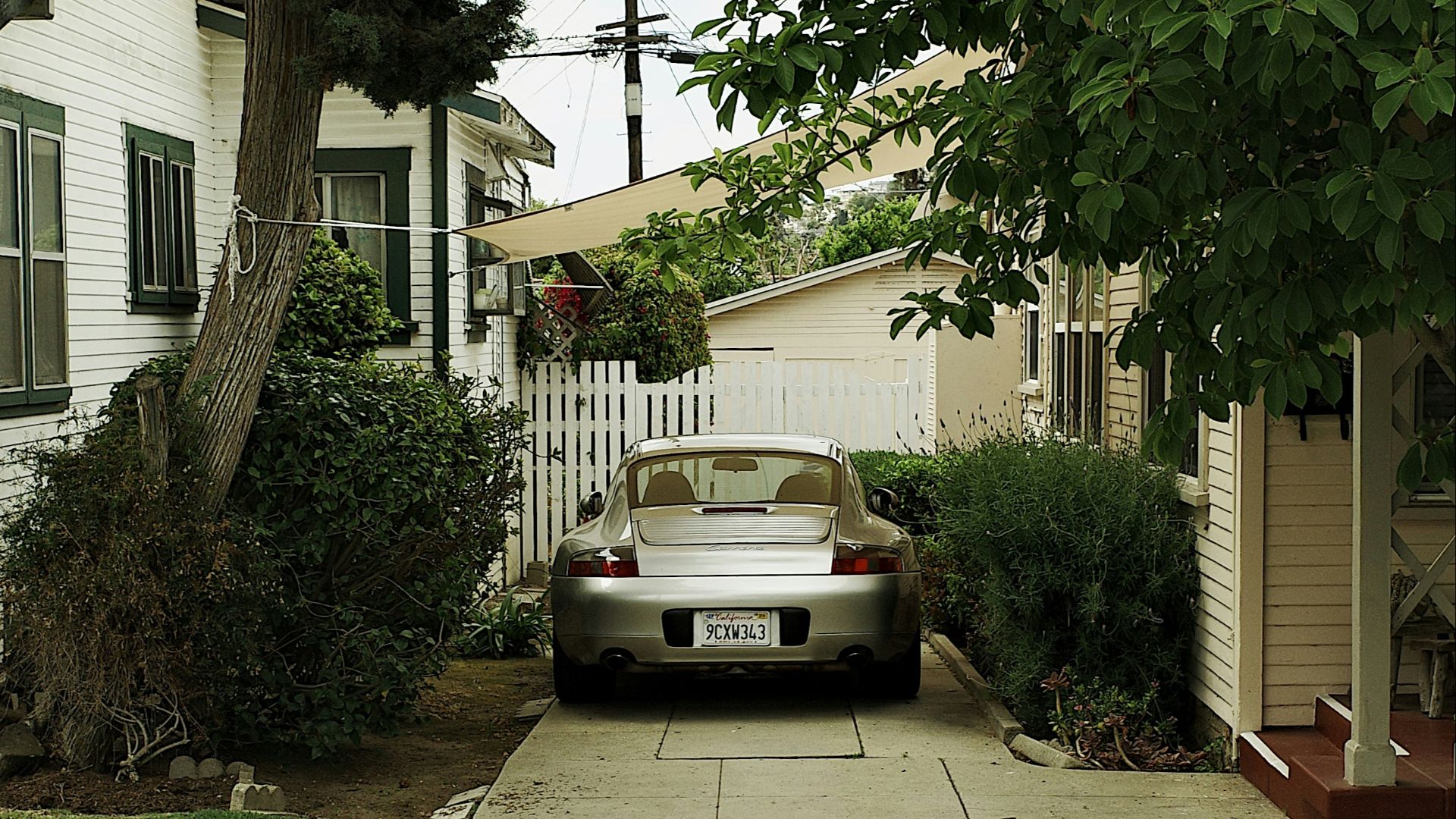 A silver car is parked on a long driveway.