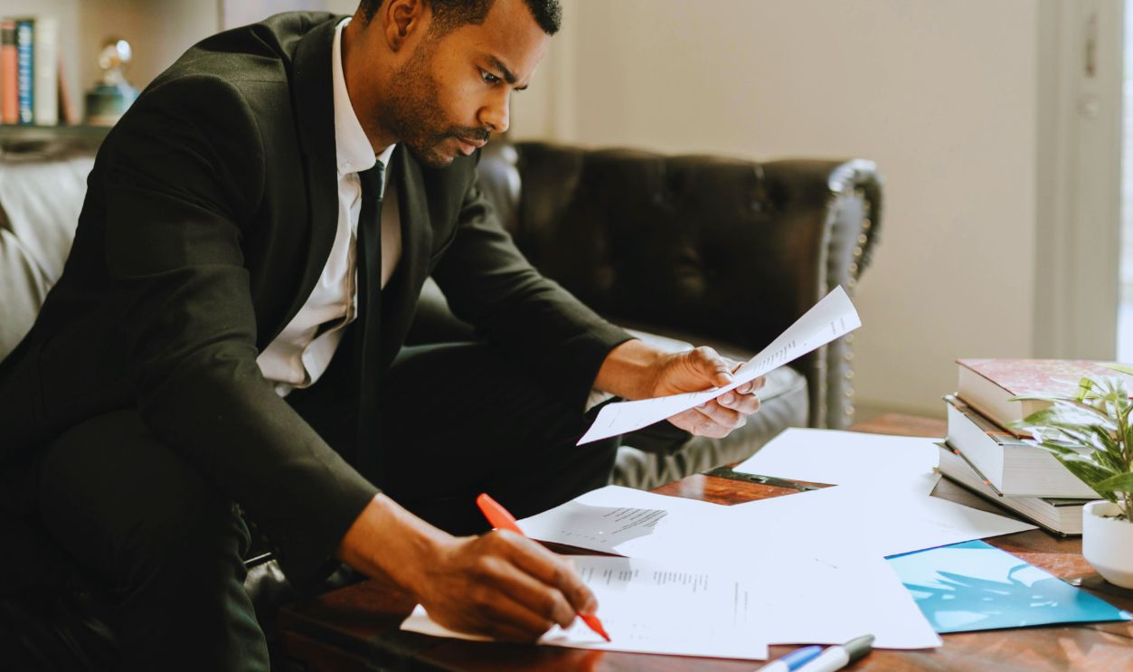 A Man in a Suit Looking at Documents on a Coffee Table