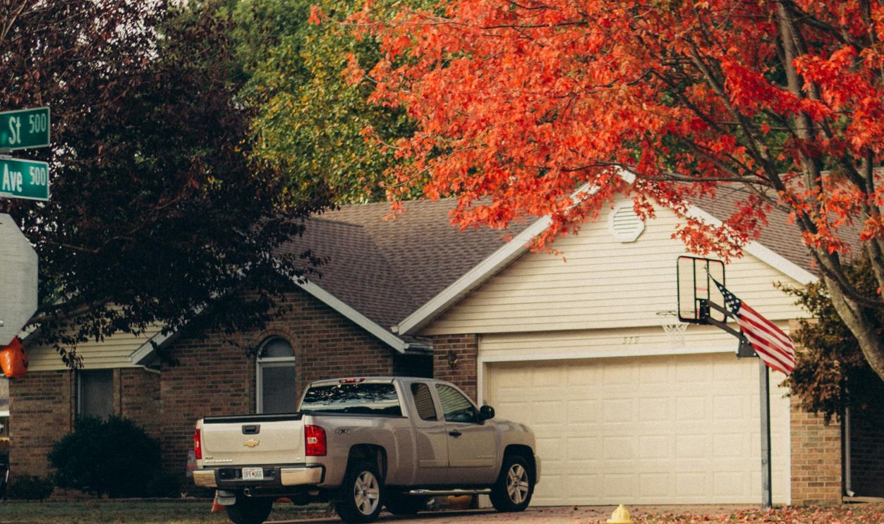 A Gray Pick-Up Truck Parked Outside a House Near Autumn Trees