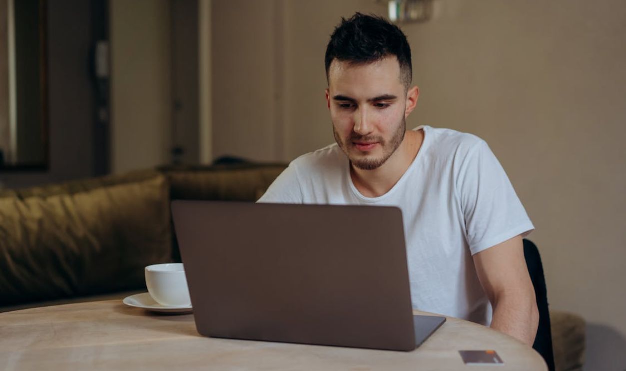 Man in White Shirt using Gray Laptop
