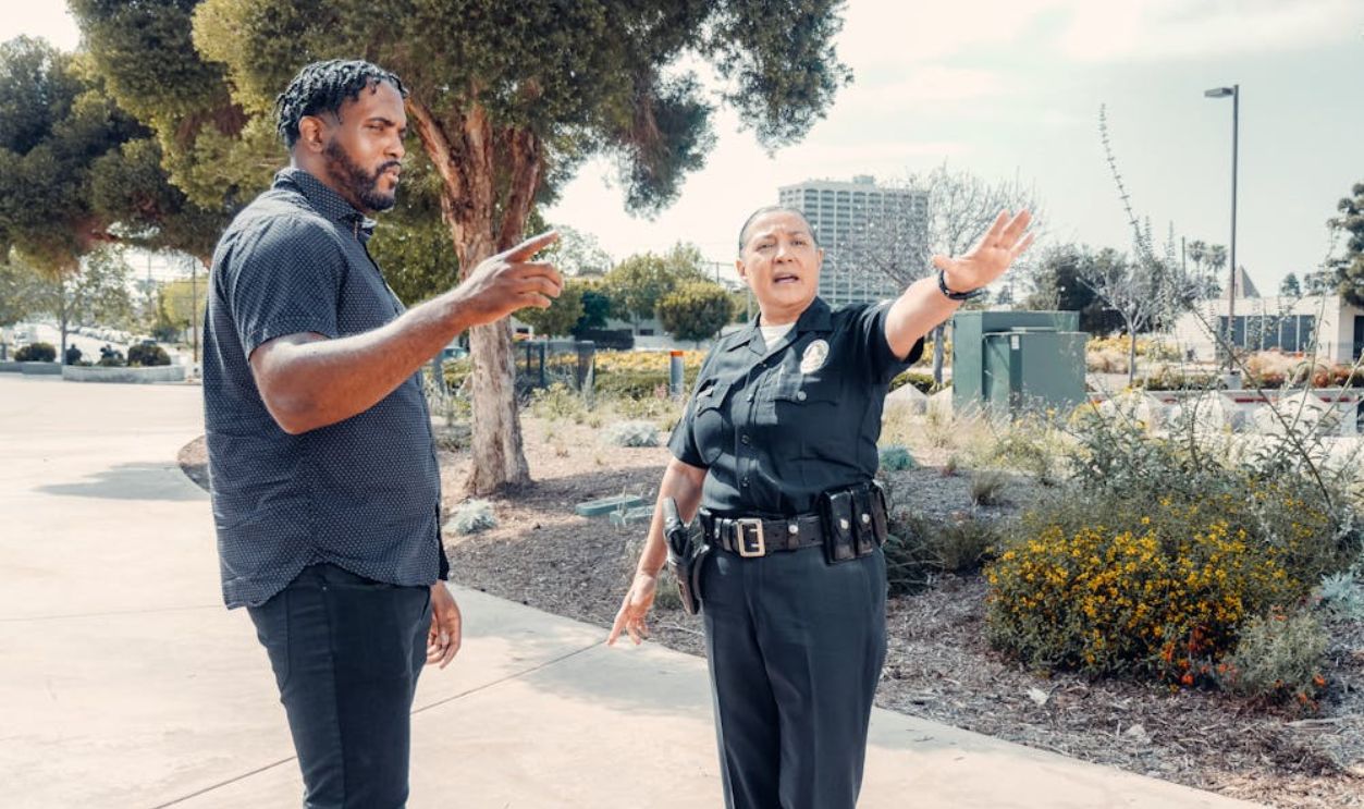 Police Officer Talking to Man in Black Shirt on the Street