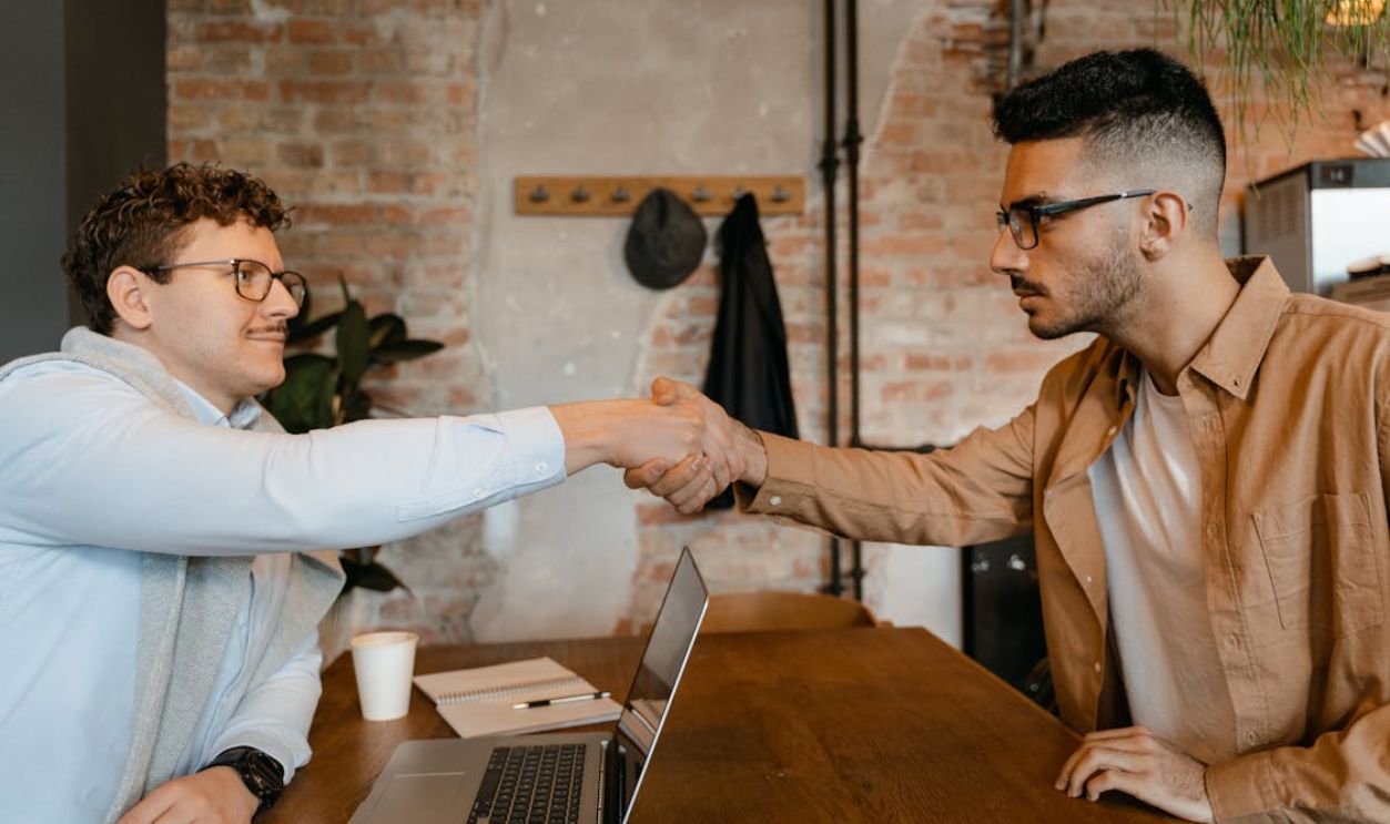 Men Sitting at a Table with Laptop Shaking Hands