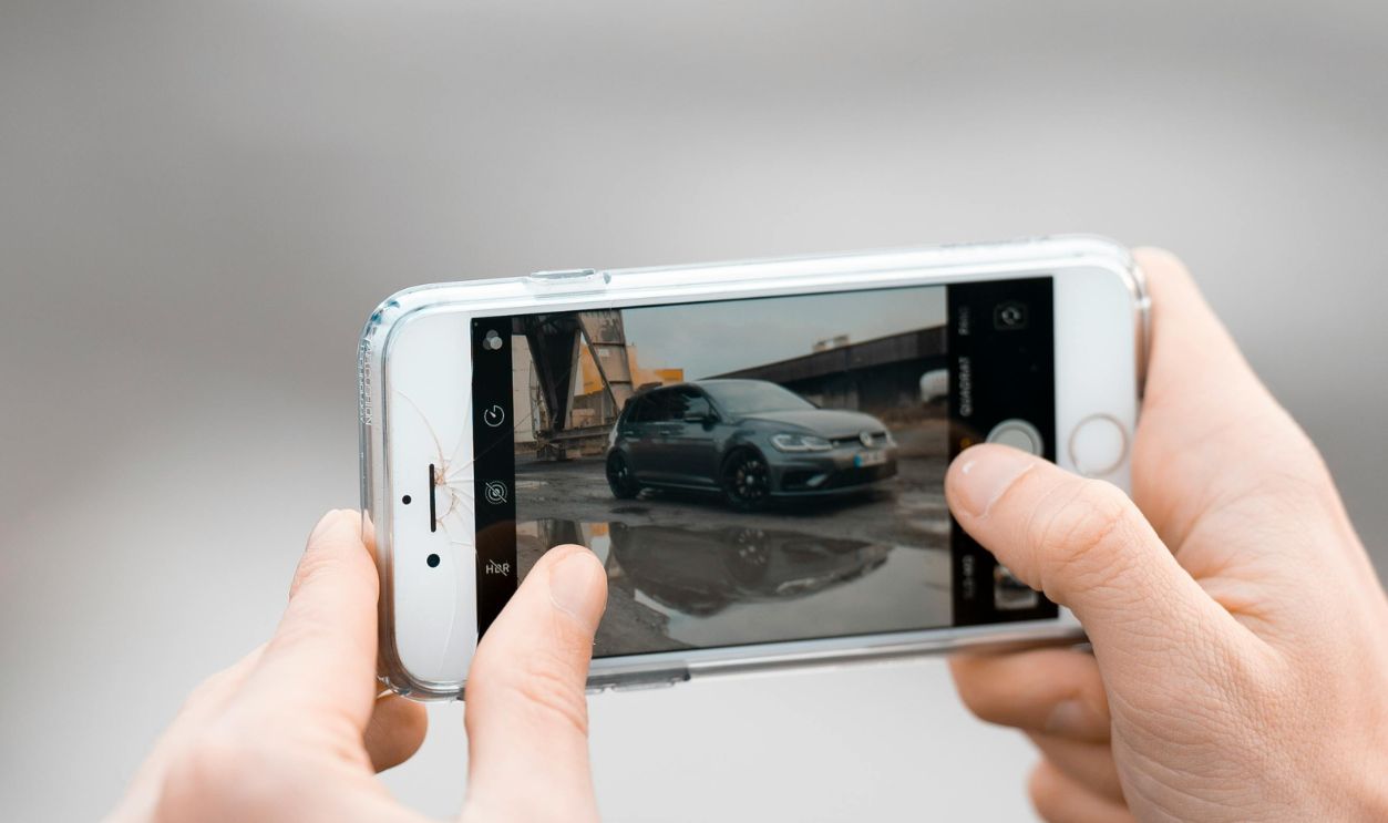 Man Photographing a Car with Smartphon