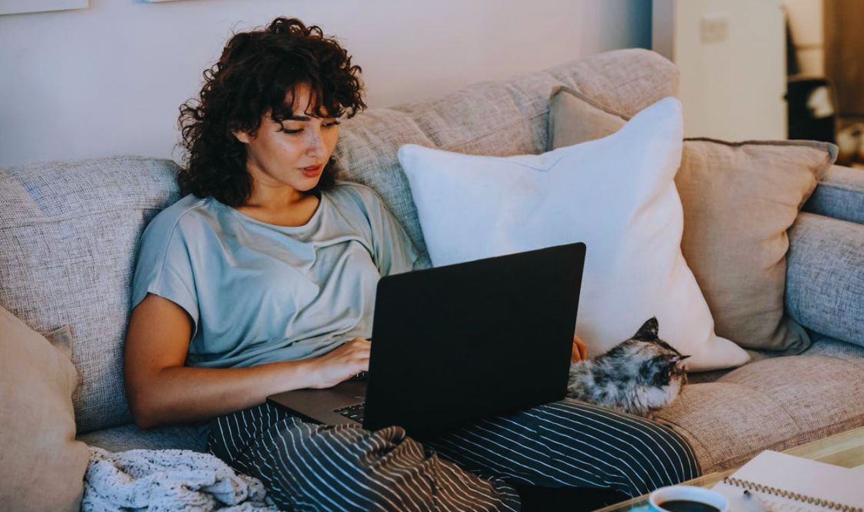Relaxed female watching movie on netbook and caressing cat on sofa