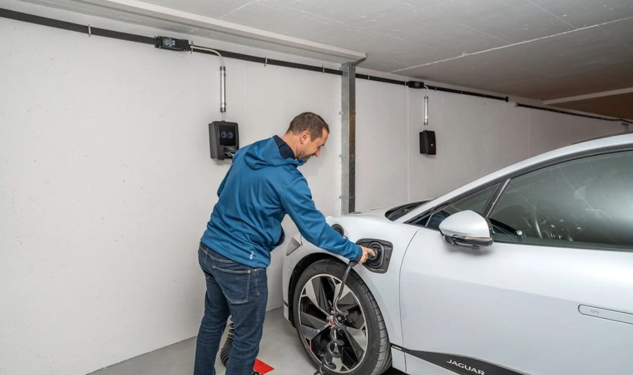 Man Charging Electric Vehicle in Indoor Garage