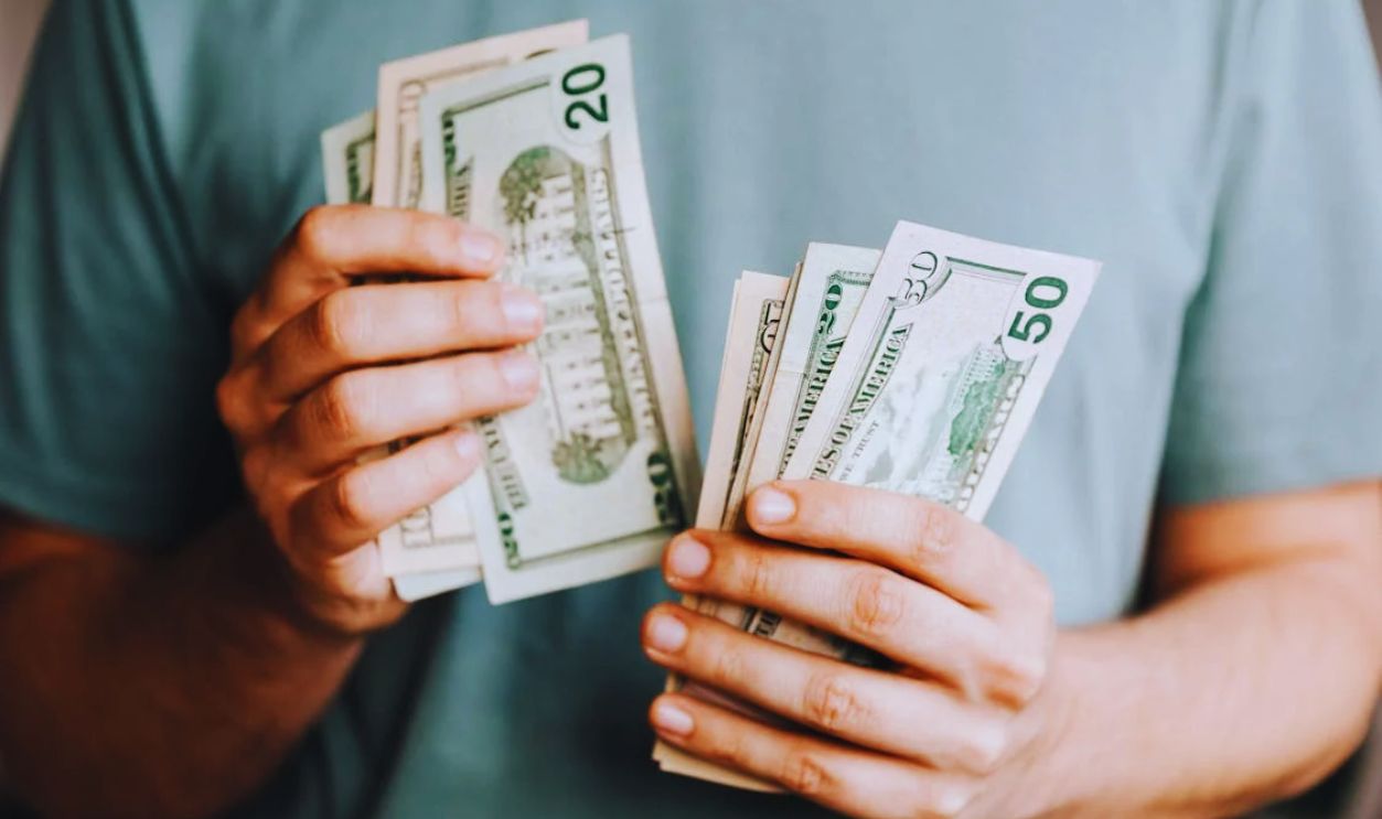 Crop man counting dollar banknotes