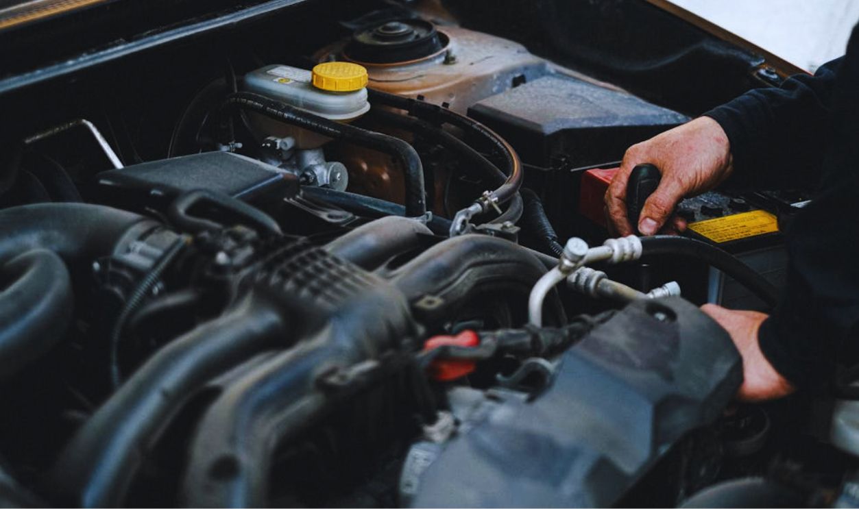 Person in Black Jacket Working on the Engine of the Car