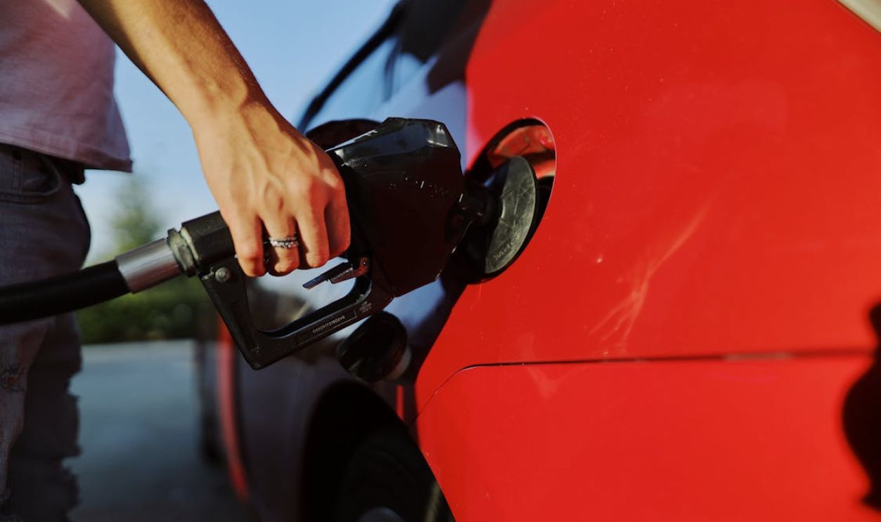 A Person Filling Up a Red Car with Gas