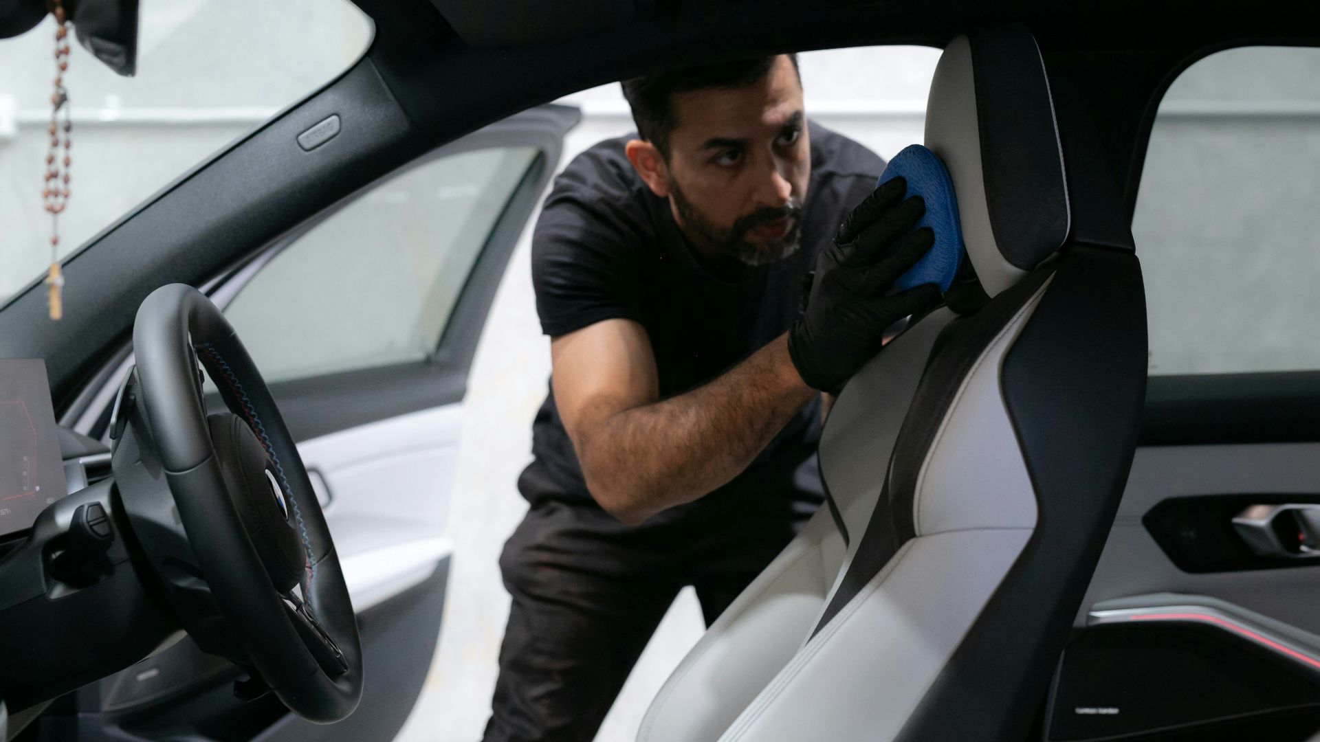 A man cleans a car seat inside the vehicle.