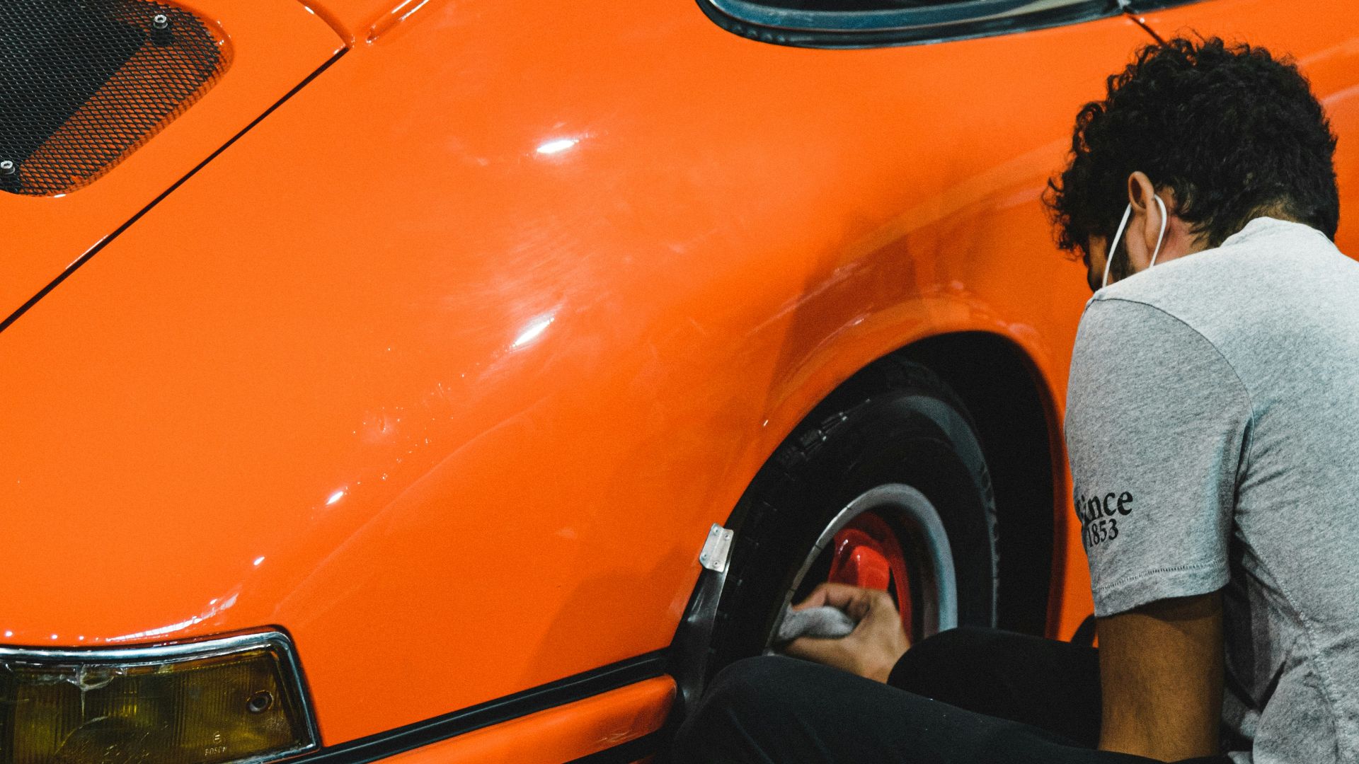 man in gray long sleeve shirt and black pants sitting on orange car