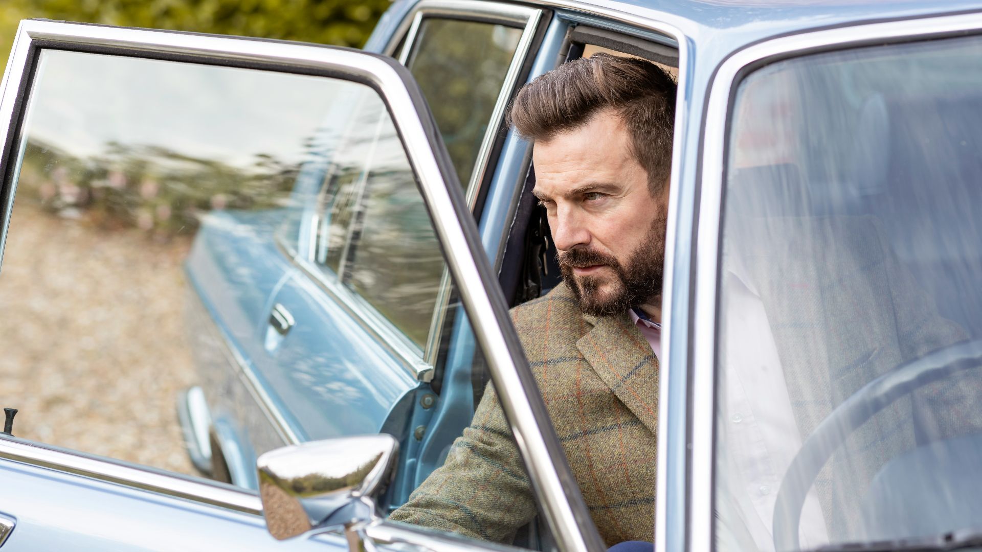 a man sitting in a car looking out the window