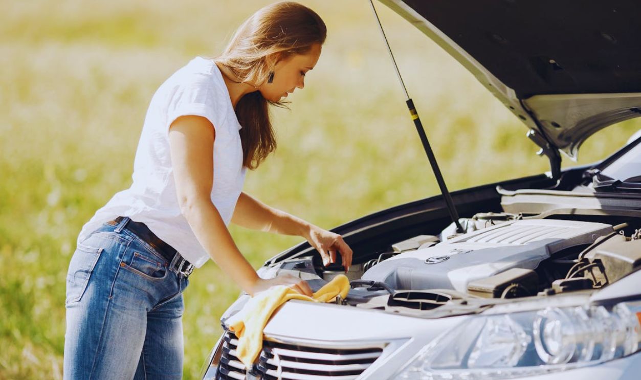 Troubled young woman near broken automobile in countryside